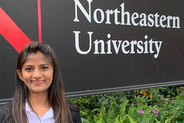 student posing in front of Northeastern University sign